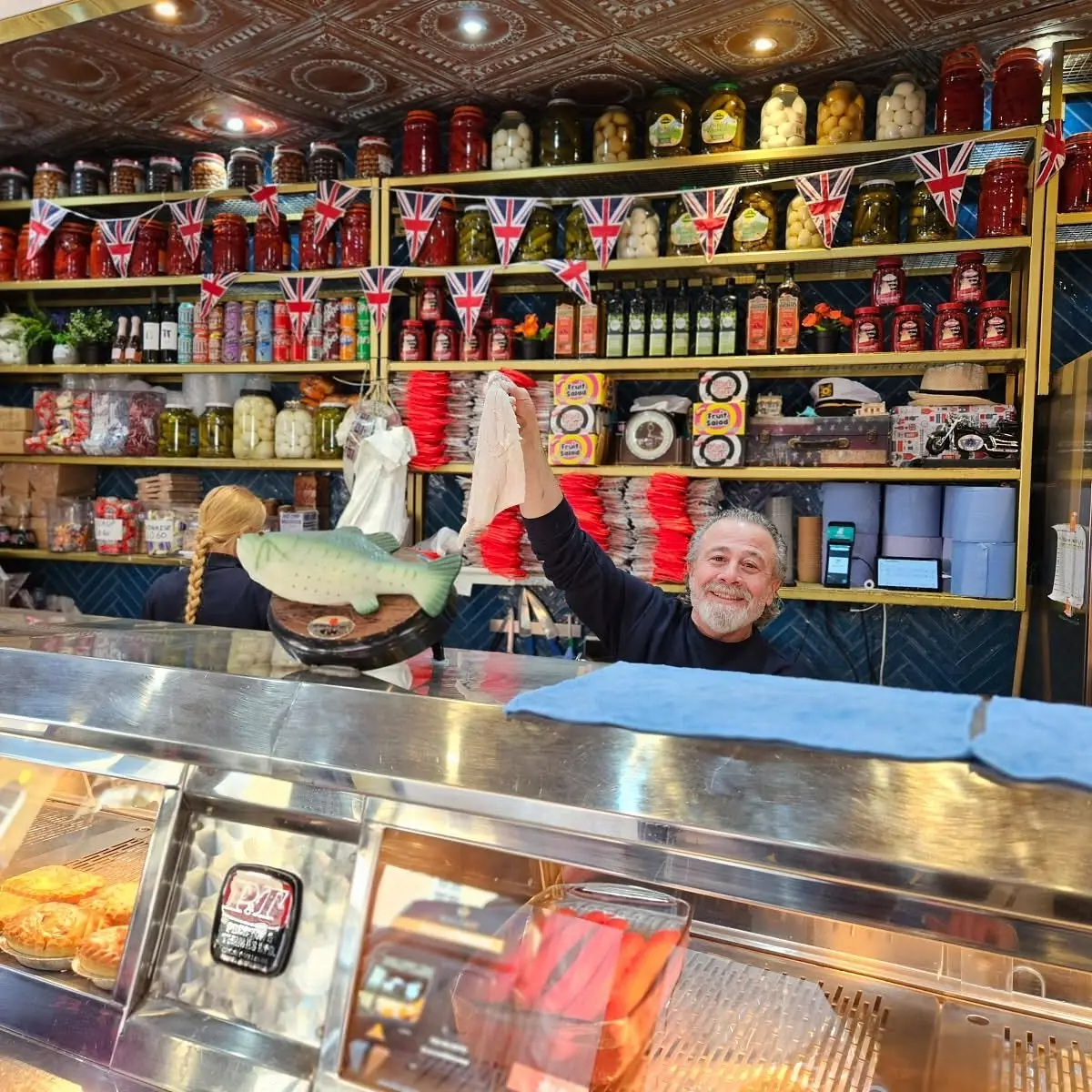 Behind the counter, with shelves of British sweets and tins on the back wall